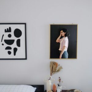 Stylish room interior featuring abstract art and a reflective mirror with a woman's portrait.